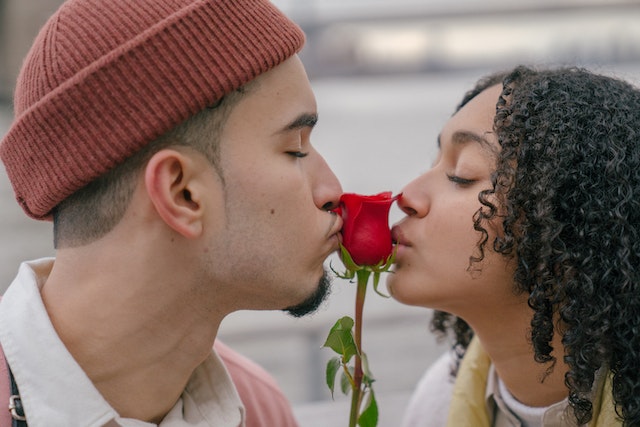 A couple kissing a rose.