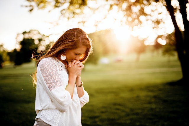 A woman praying outdoors.