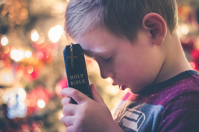 A child praying while holding the Bible.
