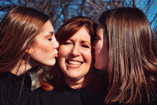 Daughters kissing their mother.