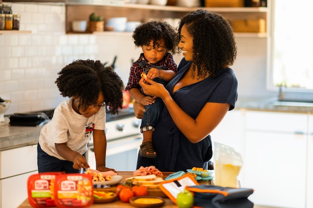 A mother teaching her kids things in the kitchen. 