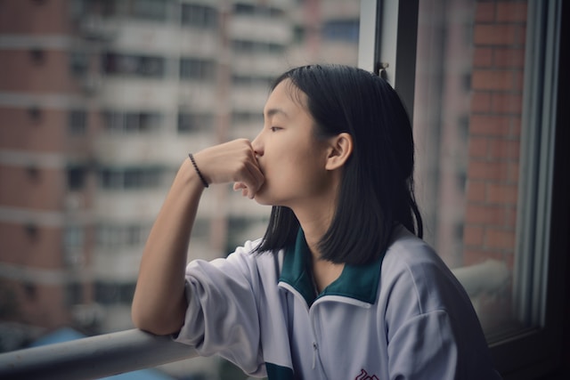 A girl staring out the window, thinking.