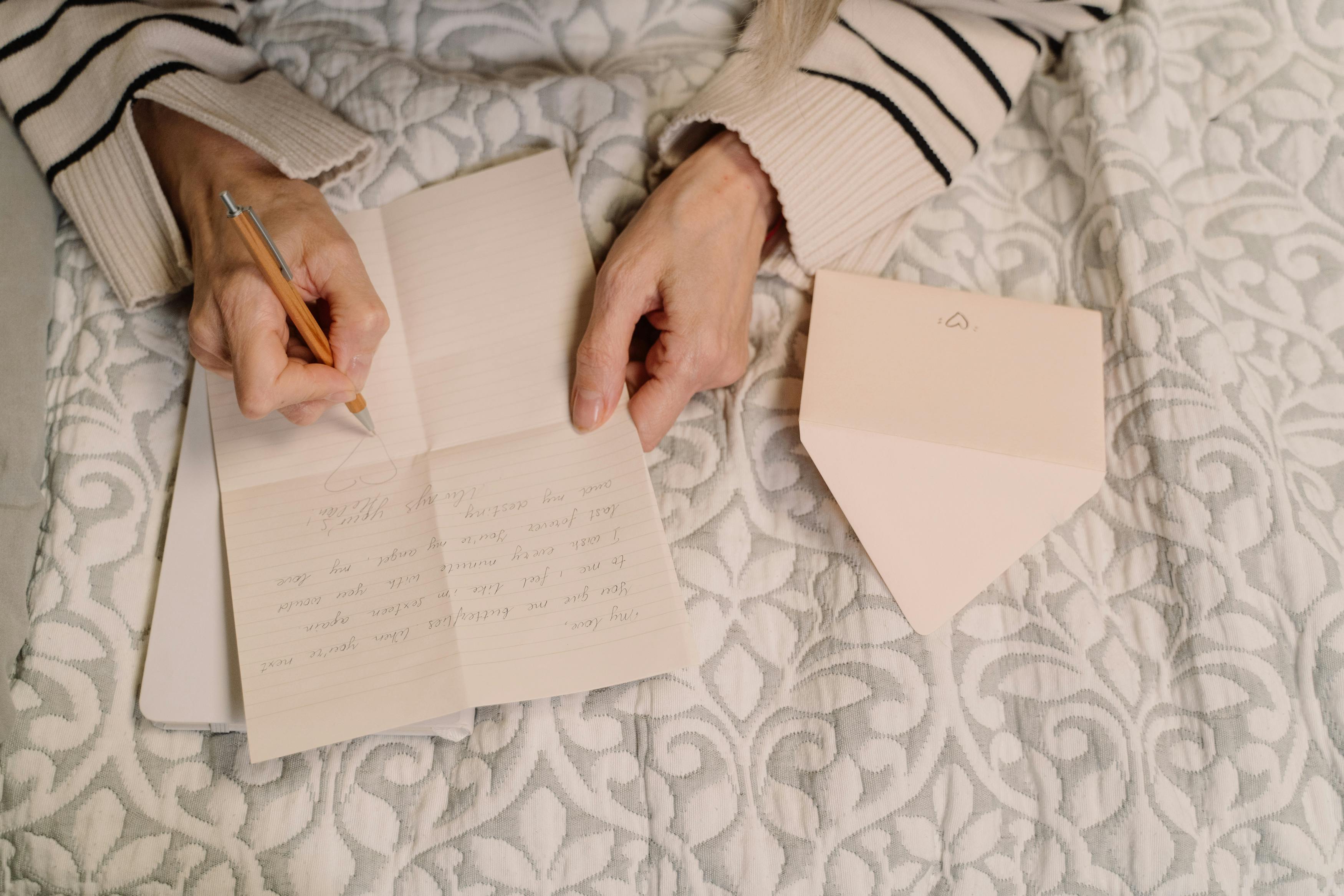 A woman's hands are shown writing a note on lined paper atop a blanket