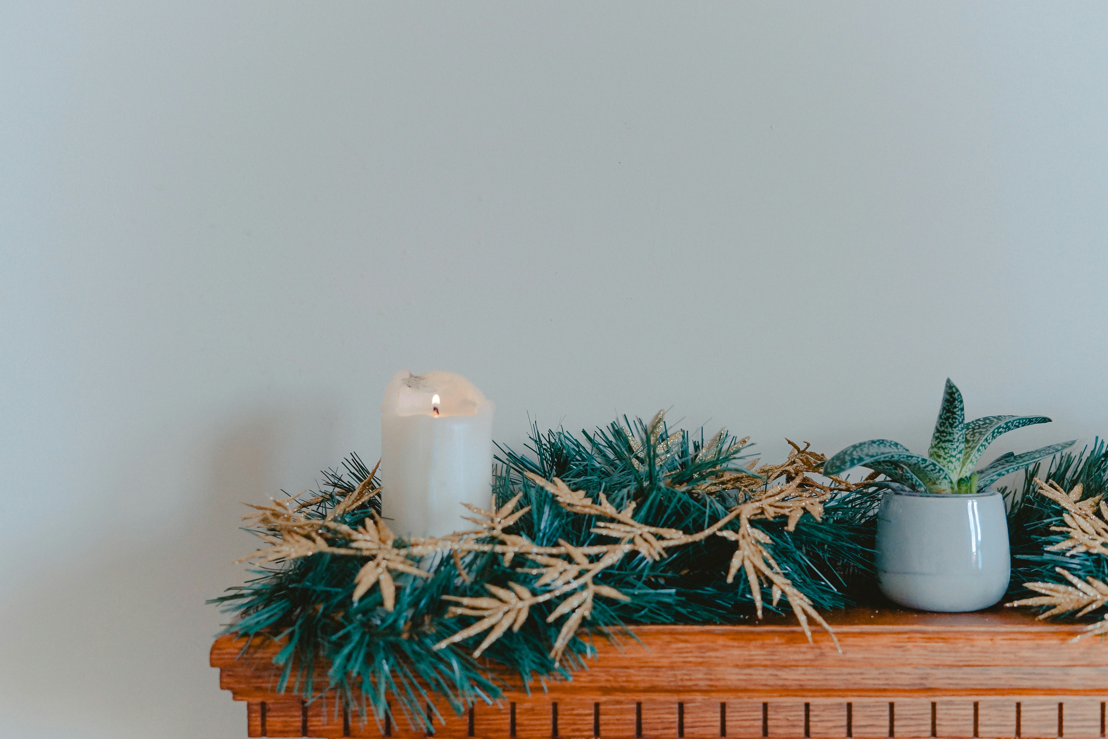 a mantel with greenery and a candle