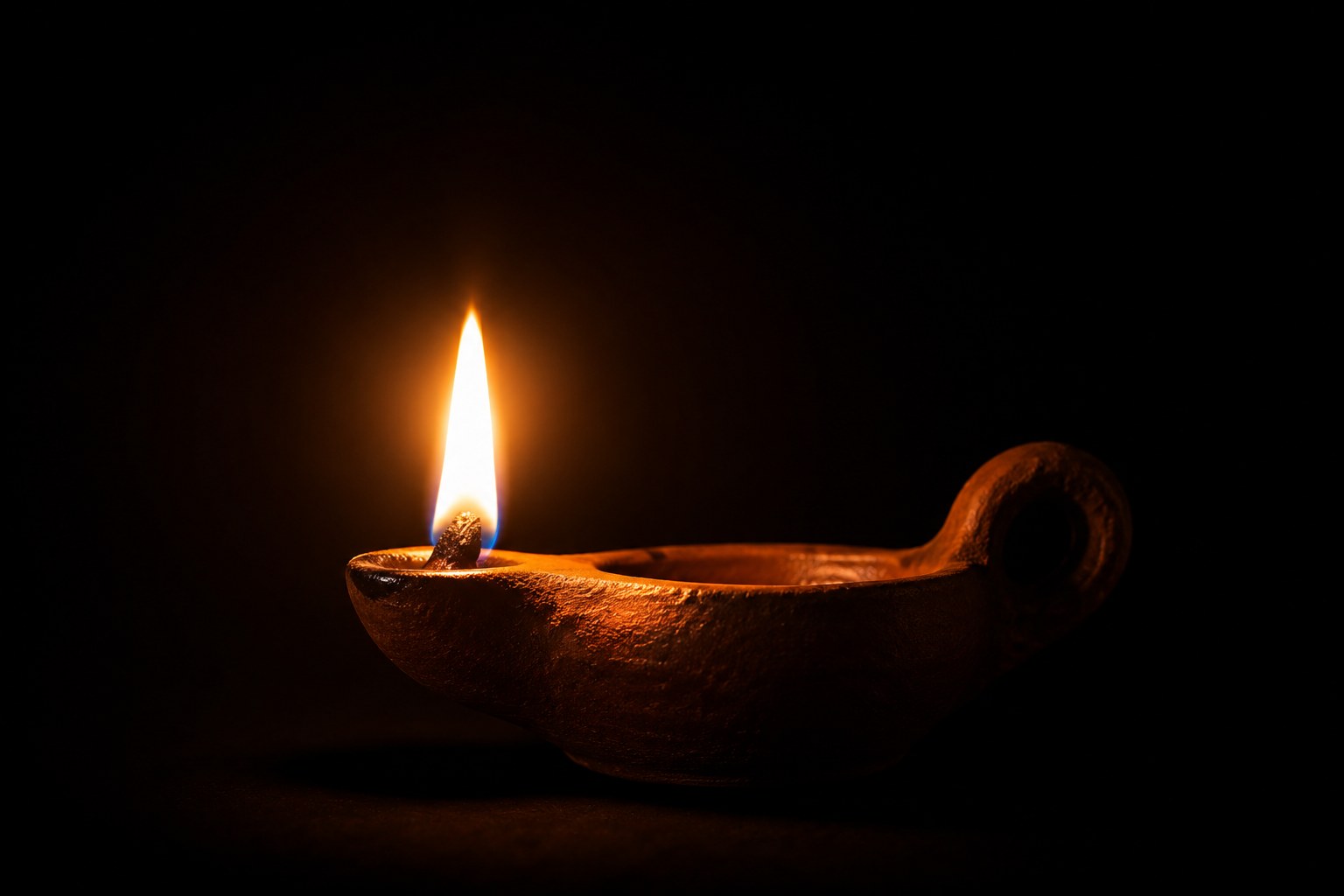 A bright oil lamp burning against a pitch-black background
