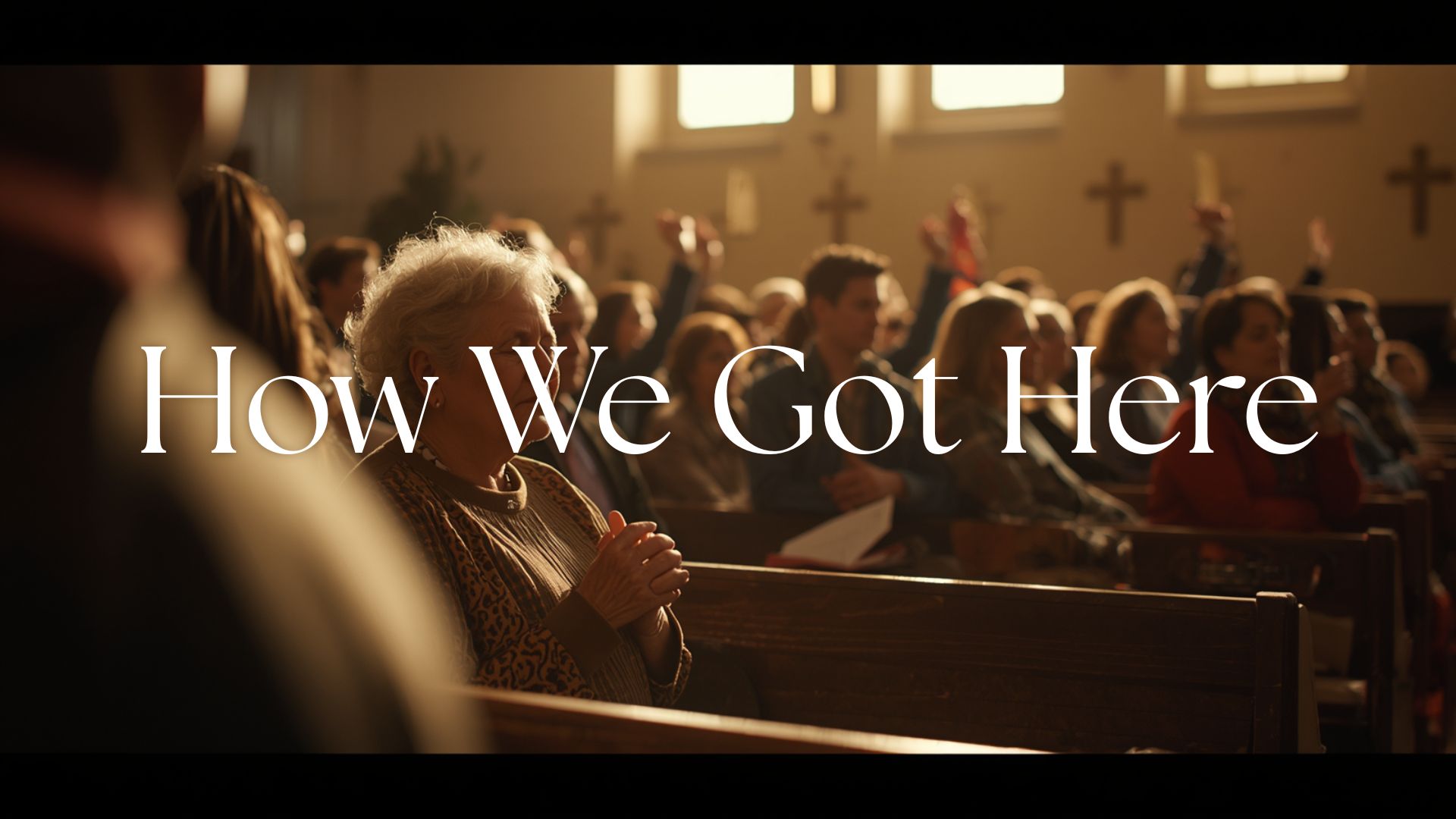 A congregation viewed from behind during a contemporary worship service. An older woman sits in the third row with hands folded and eyes closed. A young man near the back has both hands raised. A family in the middle row includes restless children and tired but present parents. Warm amber light filters through high windows.