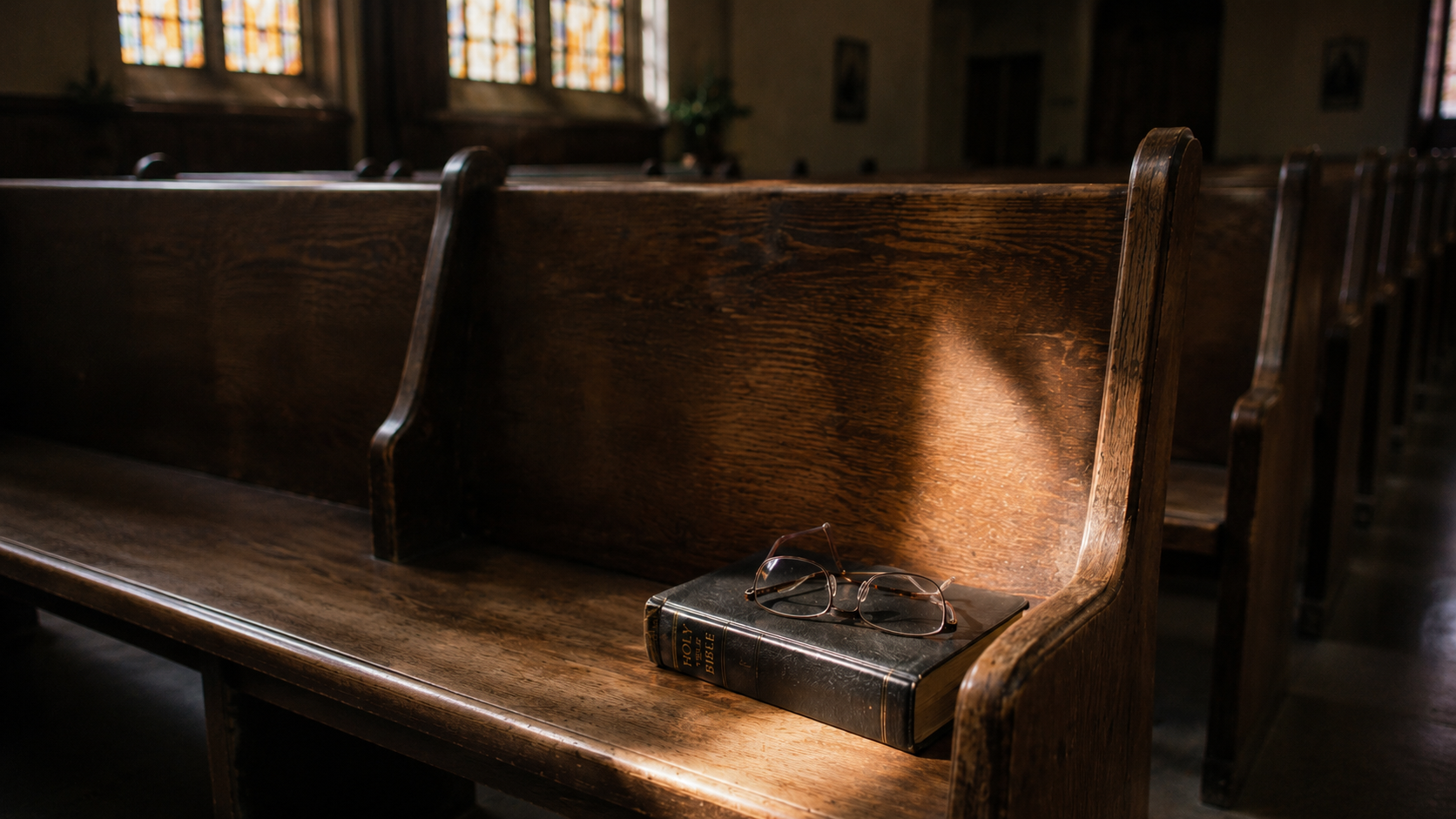  Empty church pew with reading glasses on a closed Bible, soft afternoon light suggesting a moment of quiet departure