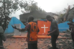 Cristãos louvam diante de igreja destruída por ciclone, em Moçambique