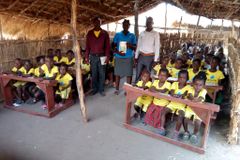 Crianças estudam sentadas na carteira pela primeira vez, em aldeia na África