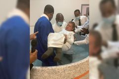 Dependente físico, homem recebe ajuda de fiéis para se batizar nas águas